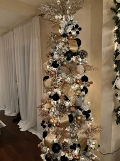 a white christmas tree with black and gold ornaments