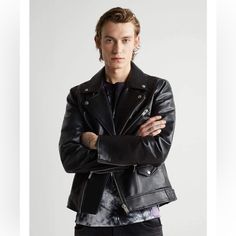 a man with his arms crossed standing in front of a white background wearing a black leather jacket