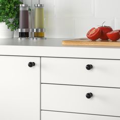 some tomatoes are sitting on top of a kitchen counter next to bottles and a cutting board