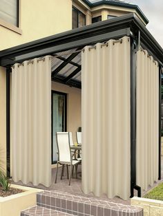 an outdoor patio covered in curtains next to a house