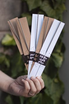 a person holding up some white and brown paper sticks with words on them that read, they let the light shine