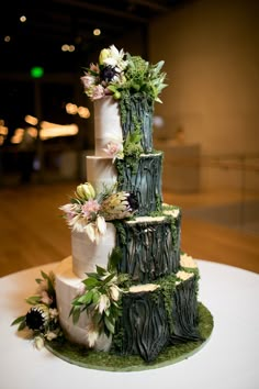 a three tiered cake decorated with flowers and greenery