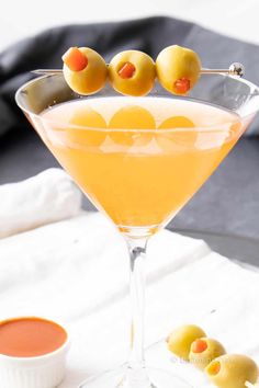 a martini with olives on the rim and an orange garnish in it