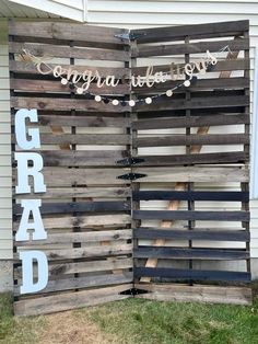 a sign made out of wooden pallets that says grad and string lights hanging from the side