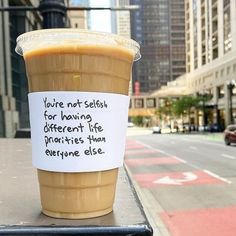 a coffee cup with a note on it sitting on a table in front of a city street