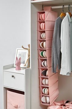 an organized closet with pink drawers and clothes hanging on the rack, next to a white dresser