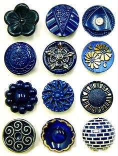 a collection of blue and black buttons on a white surface with an intricate design in the middle