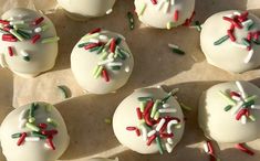 white cake balls decorated with sprinkles and colored icing on parchment paper