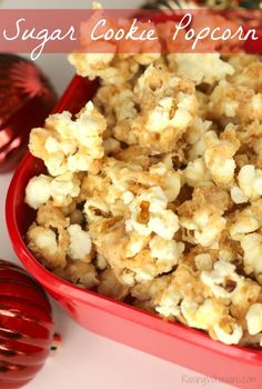 a red bowl filled with popcorn next to christmas ornaments