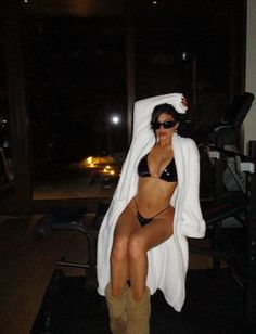 a woman in a bathing suit sitting on a chair with a towel over her head