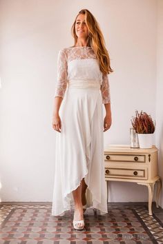 a woman in a white dress standing next to a dresser