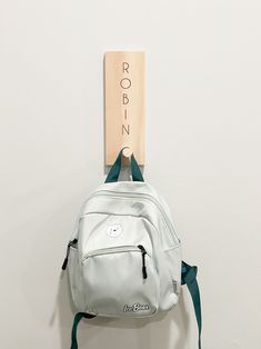 a white backpack hanging on a wall with a wooden sign above it that says robin