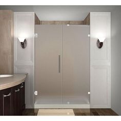 a bathroom with a walk in shower next to a white sink and brown cabinetry