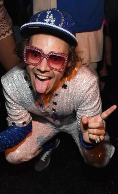 a woman with her tongue out wearing sunglasses and a baseball cap is posing for the camera