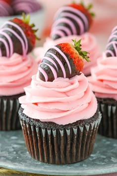 chocolate cupcakes with pink frosting and strawberries on top