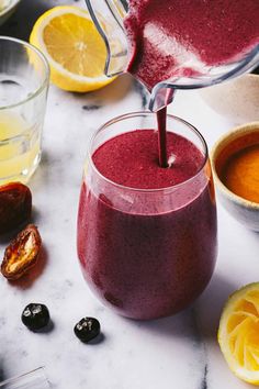 a person pouring liquid into a glass filled with fruit