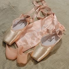 three pairs of ballet shoes on a bed