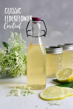 three jars filled with lemonade sitting on top of a table next to some flowers