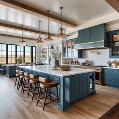 a large kitchen with blue cabinets and wooden flooring is pictured in this image, there are several stools on the island