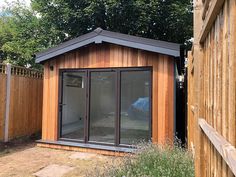 a small wooden shed sitting next to a fenced in area with grass and trees