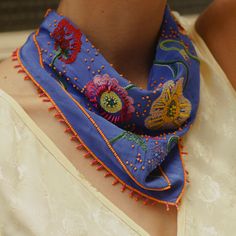 Periwinkle Bandana with Multi-Colored Flower Embroidery Styled on Model's Neck Embroidered Bohemian Scarves For Spring, Embroidered Bohemian Scarf For Spring, Bohemian Embroidered Scarves For Spring, Bohemian Party Scarves For Spring, Bohemian Silk Scarves For Spring, Traditional Floral Embroidered Scarves For Spring, Traditional Floral Embroidered Scarf For Spring, Festive Embroidered Silk Scarves, Blue Bohemian Silk Scarf For Spring