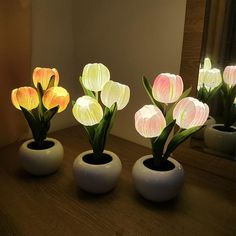 three white vases with pink and yellow tulips in them on a table