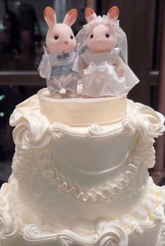 two stuffed animals sitting on top of a wedding cake