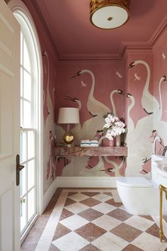 a bathroom decorated in pink and white with swans painted on the wall above the toilet