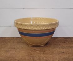 a yellow bowl sitting on top of a wooden table next to a white wall and wood floor