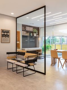 a room with tables, chairs and a bench in front of a large glass wall