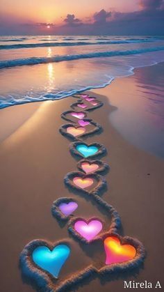 heart - shaped candles are lined up on the beach as the sun sets