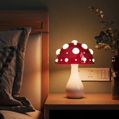 a lamp that is sitting on top of a night stand next to a bed with pillows