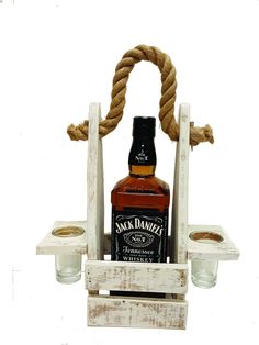 a bottle of jack daniels sitting on top of a wooden stand with two glass holders