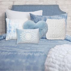 a bed with blue and white comforters, pillows and blankets on top of it