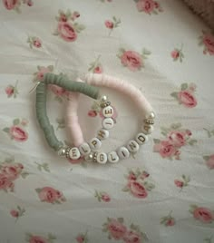 two bracelets are laying on top of a flowered bed sheet with pink flowers