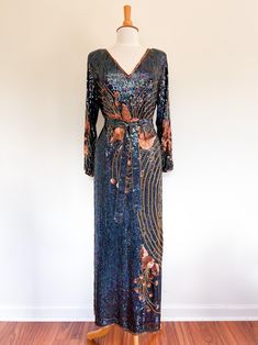 RARE 80s art nouveau full sequin gown / 100% silk / gold barrel bead trim and embellishments / iridescent sequin body and bronze sequin flowers / waist tie fit leans 70s, I think this is a very early piece / made by label "Tan-Chho" ⚡️ no labeled size, measures as a large (modeled on size small, 5'5") ⚡️ measured lying flat: shoulders 18" pit to pit 22" waist 21" hips 23" length 52" sleeve length 21.5" ⚡️ very few missing beads/sequins. there are some gold barrel beads missing in small little numbers here and there. a couple sequins missing on very small section of top right shoulder. overall this gown is in fantastic condition for how covered it is. please DM for more detailed pictures of missing beads. I would call this "very very good" condition, just short of excellent because of the f Bohemian Sequined Maxi Dress For Evenings, Bohemian Floor-length Sequined Maxi Dress, Gown Long Sleeve, Sequin Flowers, 80s Art, Iridescent Sequin, Full Length Gowns, Iridescent Blue, Sequin Gown