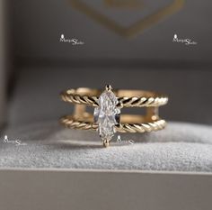 two gold wedding bands with a pear shaped diamond in the center and an oval cut diamond on each band