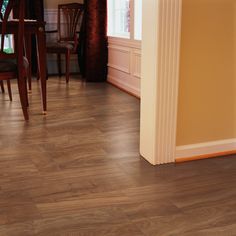 an empty room with wood floors and dining table in the corner, next to a doorway