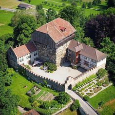 an aerial view of a castle like building surrounded by lush green fields and trees in the background