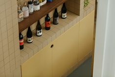 several bottles are lined up on a shelf in the corner of a tiled bathroom area