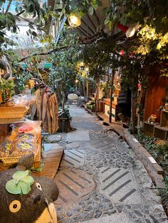 a teddy bear sitting in the middle of an alley way surrounded by trees and plants