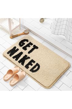 a bathroom rug with the words get naked on it and slippers next to it