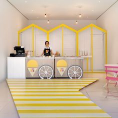 a woman standing behind a counter in a room with yellow and white stripes on the floor