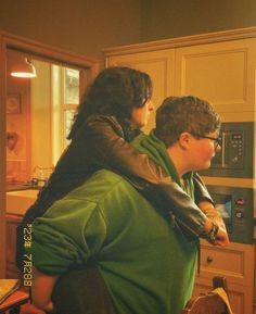 two people standing in a kitchen next to an oven and counter top, one holding the other's back