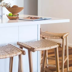 two wicker stools sitting on top of a kitchen counter next to a bowl of fruit