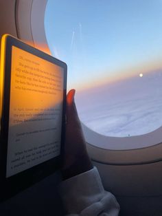 someone is reading a book while flying in an airplane