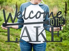 a woman standing in front of a sign that says welcome to the lake