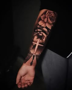 a person with a cross and rose tattoo on their arm