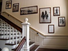 a staircase with pictures on the wall and wooden banisters in front of it