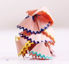 an origami christmas tree made out of colored pencils on a white surface